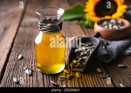 Sunflower oil in a glass jar, decorated with whole seeds and flowers on wooden table Stock Photo