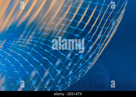 Dynamic detail of abstract airy net and orange light rays on a blue background. Beautiful mesh of azure toned fibers on rastered texture in navy shade. Stock Photo