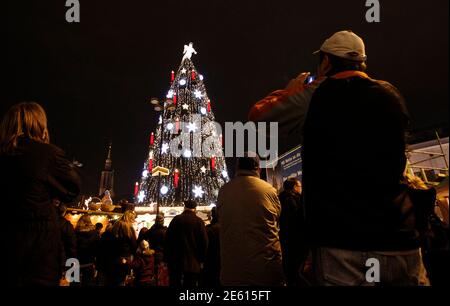 People gather around a decorated Christmas tree at a Christmas market on its opening day in Dortmund November 22, 2010. The Christmas tree of Dortmund is the largest in the world and is built with a scaffold, covered with 1,700 Norway spruces, 40,000 lights and is 45m (148 ft) high.  REUTERS/Ina Fassbender (GERMANY - Tags: SOCIETY)