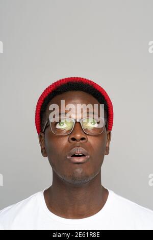 African American hipster man wear red hat in glasses wear thinking, looks up in surprise isolated Stock Photo