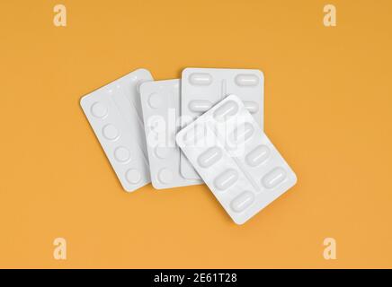 Packets of medication in a pile on an orange background, stack of blister packs Stock Photo