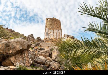 Tower ruins with Omani flag into the hills of the old village Misfat Al Abriyeen, Sultanate of Oman Stock Photo