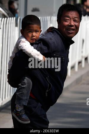 A man carries his son on his back as he walks down a street in central Beijing April 28, 2011. China's mainland population grew to 1.34 billion by 2010, according to census figures released on Thursday, up 5.9 percent from the 1.27 billion counted in the last census in 2000, and lower than the 1.4 billion population some demographers had projected for the latest tally. The Chinese government's strict controls on family size, including a one-child policy for most urban families, have brought down annual population growth to below one percent and the rate is projected to turn negative in coming 