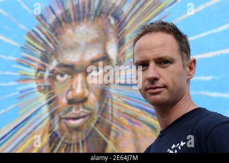 Street artist James Cochran, also known as Jimmy C, poses near his spray painted picture of Jamaican sprinter Usain Bolt in Sclater street car park in east London July 19, 2012. Cochran said this was done as an homage to the London 2012 Olympic Games, which begin July 27. REUTERS/Paul Hackett  (BRITAIN - Tags: SPORT OLYMPICS ATHLETICS ENTERTAINMENT)