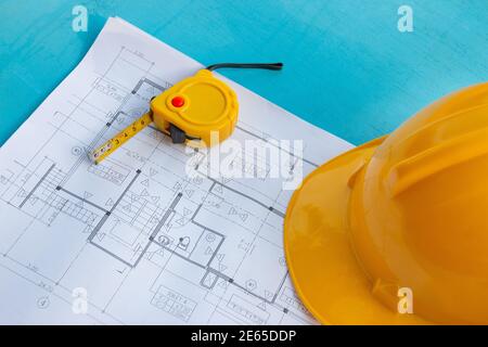 Construction drawings, safety helmets and tape measure on the blue wooden background Stock Photo