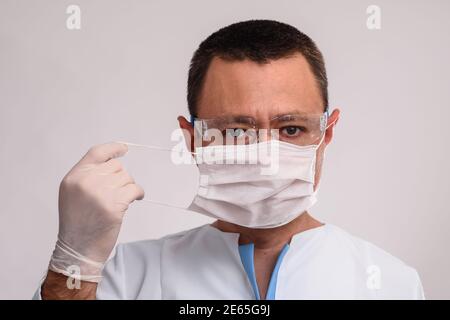 Professional doctor putting on protective face mask. COVID-19 preventive measures.  Stock Photo