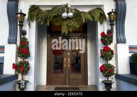 Front entrance of an old apartment building decorated with a Christmas wreath, green cedar boughs, and topiary Stock Photo