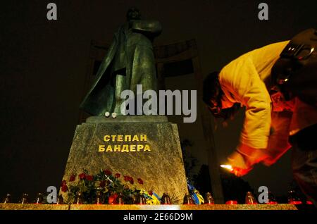 A woman lights a candle in front of a monument of Stepan Bandera, one of the founders of the Organization of Ukrainian Nationalists (OUN), during his 51st death anniversary in central Lviv, October 15, 2010.  REUTERS/ Konstantin Chernichkin (UKRAINE - Tags: POLITICS ANNIVERSARY)