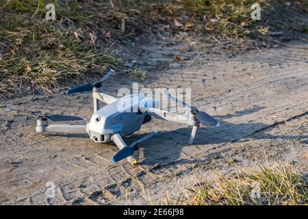 The drone is standing on the ground and ready to take off. Close-up of the assembled gray drone. Flying UAV with a pendant camera and remote control. Stock Photo