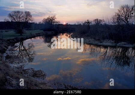 amazing sunset over the river with a mirror reflection of clouds in the water. on river Goryn , in Ukraine. March Stock Photo
