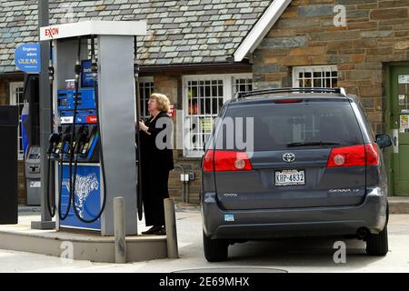 A woman operates a gas pump at an Exxon station next to the Watergate complex in Washington March 2, 2012. Gasoline (regular grade) prices hover at one-tenth of a cent under the $5.00 mark at this station. President Barack Obama said on Thursday his administration will lay out 'as many steps as we can' in coming weeks to unclog bottlenecks that are helping to push up the price of gasoline and other fuels. REUTERS/Gary Cameron  (UNITED STATES - Tags: ENERGY TRANSPORT)