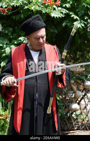 Senior Kuban Cossack checks blade of saber in the garden Stock Photo