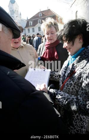 People sign a petition against the raising of electricity tariffs President Valdis Zatlers's office in Riga March 24, 2011. Several NGOs staged protests against austerity measures and dropping living standards on Thursday. The sign reads 'Stop the genocide'. REUTERS/Ints Kalnins (LATVIA - Tags: POLITICS CIVIL UNREST)