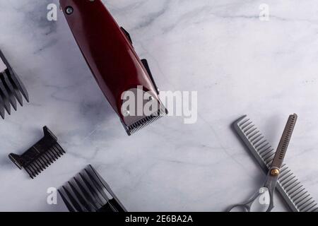 Flat lay close up image of a hair trimming kit featuring a corded electrical hair clipper with different sizes of comb guards, thinning shear type sci Stock Photo