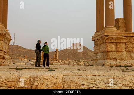 Palmyra, Syria 04-02-2010: A European tourist couple is visiting the ancient ruins of UNESCO world Heritage site at Palmyra. Stone columns are seen as Stock Photo