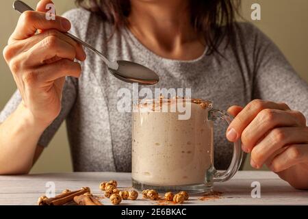 Woman eating a viscose malted barley, wheat beverage served in a cup with roasted chickpeas (leblebi) and cinnamon powder. This seasonal drink popular Stock Photo