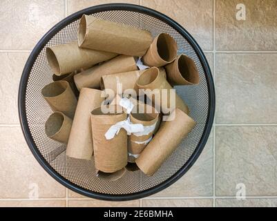 Flat lay top view image of a metal trash bin full of empty toilet paper rolls with some paper leftovers stuck on them. A concept image for buying, hoa Stock Photo