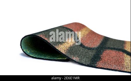 Dark green, yellow, and orange shingle roof on white background. Roofing material. Shingle roof texture. Shingle roof made from asphalt, plastic fiber Stock Photo
