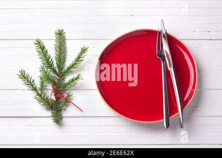 Red vintage plate with cutlery and branch of a Christmas tree on a white background Stock Photo