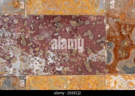 Corroded rusty background. Peeled mottled wall streaked with rust. Oxidized abstract spots on the damaged surface. Rotting corrosion. Close-up Stock Photo