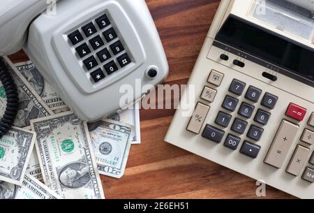 Old fashioned calculator, telephone and dollars on desk Stock Photo