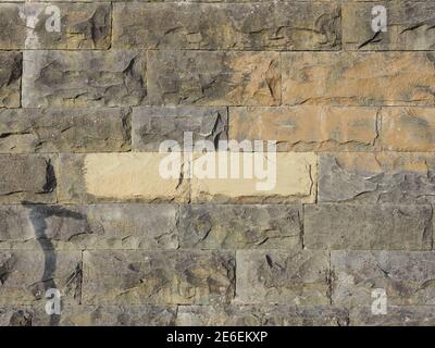 Wall with embossed rectangular stone tiles with a rough texture and spots of paint on it Stock Photo