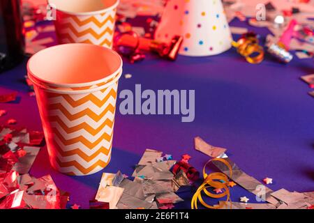 Party tinsel and colorful cups close up on purple background Stock Photo