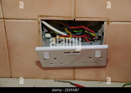Fitting a new socket with USB charging points on the front and safety checking the wiring in a home kitchen. Stock Photo