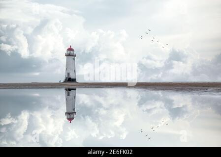 Lighthouse standing pool of water stunning dramatic storm clouds reflection reflected water sea steps up to building Wales seashore sand beach still Stock Photo