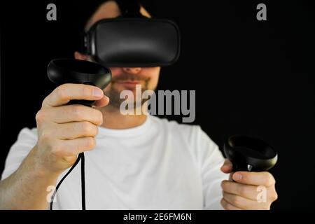 Man wearing VR headset and using hand controllers in virtual reality. Stock Photo