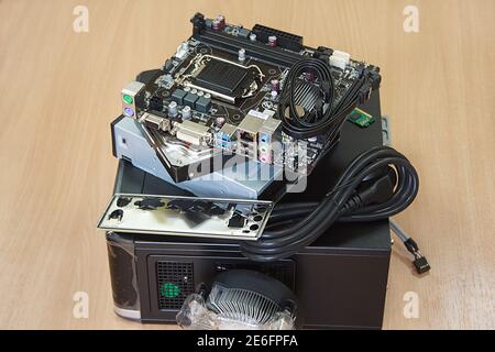 Accessories for assembly of personal computer are lying on wooden desk. Stock Photo