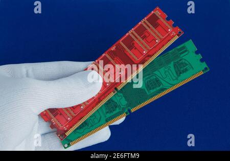 Hand in white glove holds two computer memory cards. Closeup. Isolated on a blue background. Stock Photo
