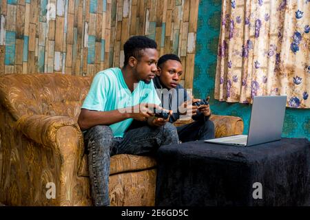 young black men playing a video game on a laptop at home Stock Photo