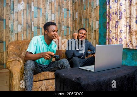 young black men playing a video game on a laptop at home Stock Photo