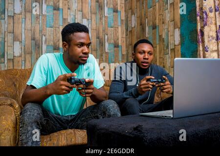 young black men playing a video game on a laptop at home Stock Photo