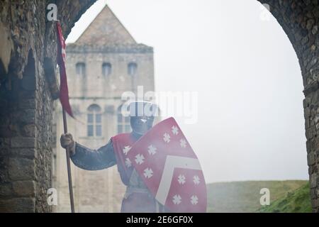 Medieval English knight stands at castle entrance Stock Photo