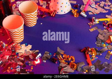 Party tinsel and colorful cups close up on purple background Stock Photo