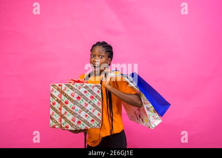 young black beautiful lady holding some shopping bags and a wrapped box of gift with great happiness Stock Photo