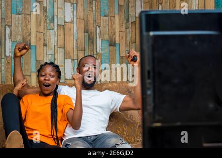 young black people isolated, watching television and having fun at home Stock Photo