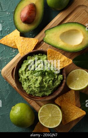 Concept of tasty eating with bowl of guacamole on green textured background Stock Photo