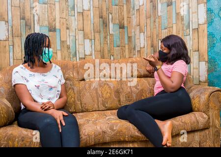 young black ladies sitting on a couch, discussing and making some jokes Stock Photo