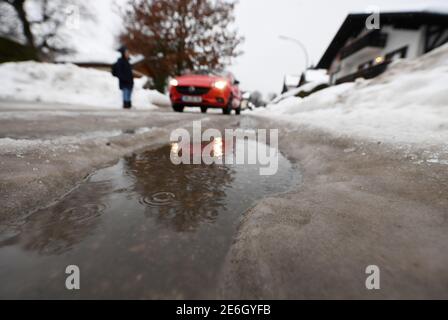 Garmisch Partenkirchen, Germany. 29th Jan, 2021. Large puddles of rain form in the streets between mountains of snow. Credit: Angelika Warmuth/dpa/Alamy Live News