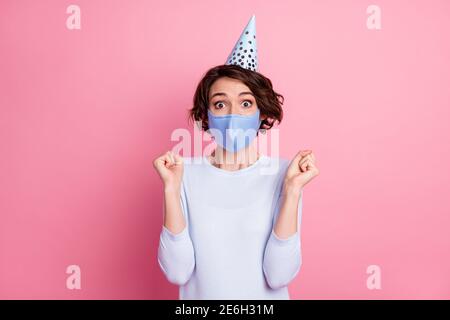 Portrait of delighted girl in medical mask raise fists wear birthday cap jumper sweater isolated pastel color background Stock Photo