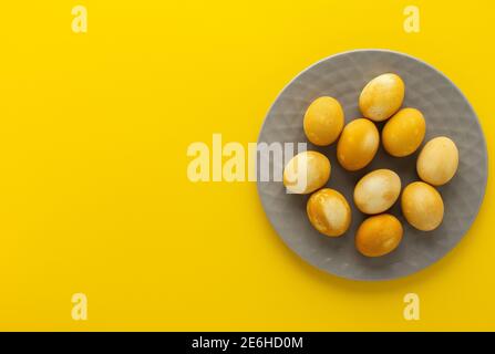 Easter golden painted eggs in gray plate on yellow background, easter festive concept Stock Photo