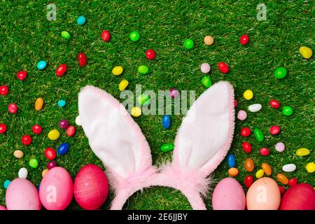 Colored eggs and vibrant candies on grass. Easter composition Stock Photo
