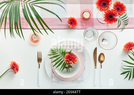 Effortless golden birthday dinner table decor. Vibrant Summer flat lay. White dinner table, white and gold utensils. Summer decor with peony flowers Stock Photo