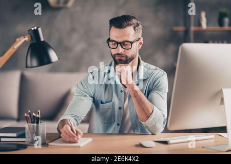 Photo portrait of guy taking notes in notebook at table in modern industrial office indoors Stock Photo