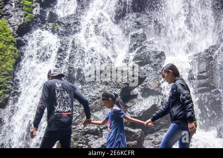 Batu City, Indonesia. November 2020. the family is enjoying the freshness of the Watu Lumpang waterfall. parents and children are on vacation in fresh Stock Photo