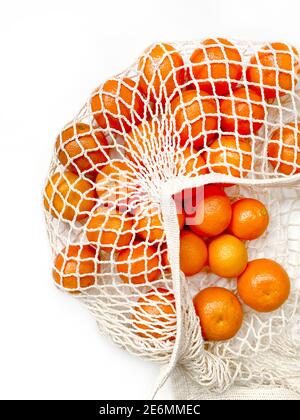 Mesh bag of fresh oranges healthy citrus fruits from on white background. Flat lay, top view. Stock Photo