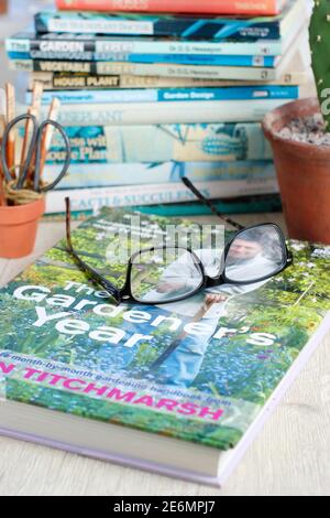Gardening books. UK. Gardeners glasses on a stack of her gardening books. Stock Photo